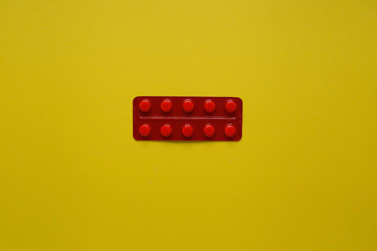 Tablets in a blistered red package on a yellow background from above