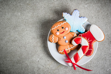 Plate with homemade colorful glazed Christmas cookies on stone gray table, top view copy space