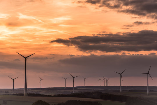 Wind turbines and beautiful orange sunset sky. Representing clean energy as the power source of the future. Struggle against global warming. Hosingen, Oesling in Luxembourg.