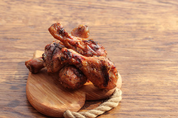 Grilled chicken legs on cutting board. Rustic dinner background