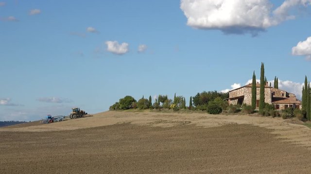 Tractor working in a field near the old manor. Tuscany, Italy