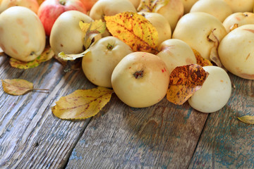 Apples with yellow leaves wooden table.