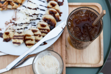 Delicious ice coffee americano with waffles and banana in back