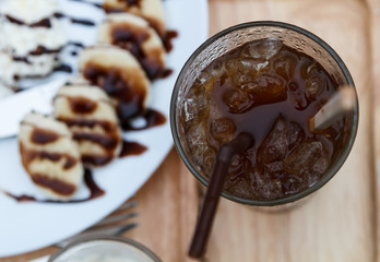 Top view of ice coffee americano with waffles and banana in back