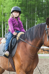 Little Caucasian girl is riding a horse