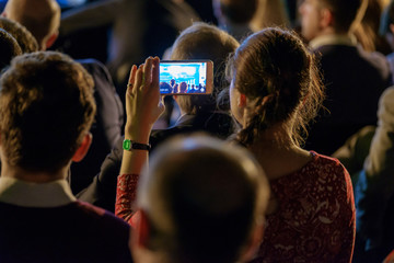 Woman takes a picture of the presentation at the conference hall using smartphone