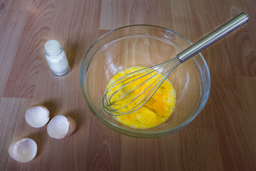 Making omelets, fresh raw eggs in a glass bowl on the kitchen table, salt, cooking