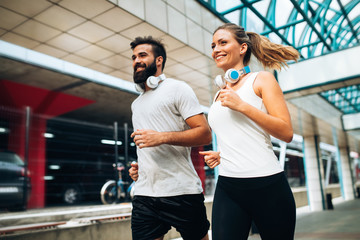 Young fitness couple running in urban area