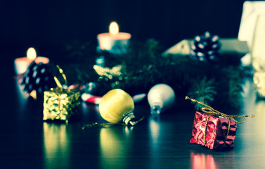 New Year's gifts on a wooden table with candles and a Christmas tree with cones. Vintage, grunge old retro style.