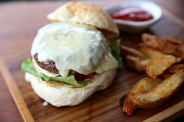 Beef hamburger with cheese and fires on wood background