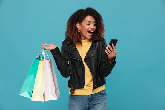 Excited amazing young african woman holding shopping bags