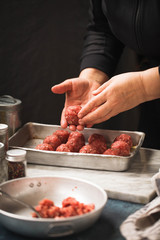 Raw beef meatballs tray of raw meatballs being prepared by a cook