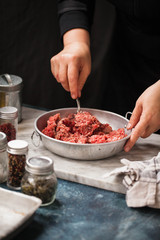 Minced meat mixture for meatballs and ingredients on dark table 