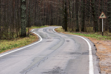 Curved empty road in woods in late autumn. Serene landscape
