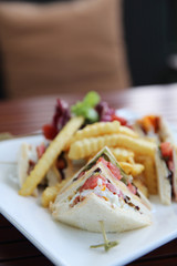 Club sandwich with chicken breast , bacon , tomato , cucumber and fried potatoes