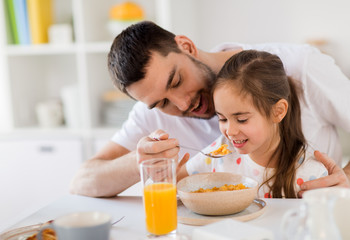 Obraz na płótnie Canvas happy family eating flakes for breakfast at home