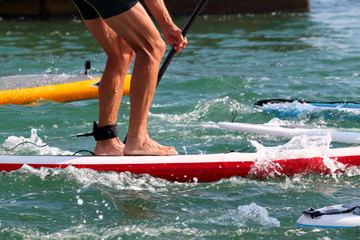 Paddle board man doing stand-up paddleboard on ocean. Athlete paddleboarding on SUP surf board on Hawaii beach travel. Closeup of legs standing on board.