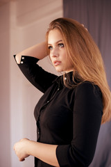 Close-up portrait of a smiling beautiful blonde caucasian woman with blue eyes, looking at camera, on a gray background with copy-space