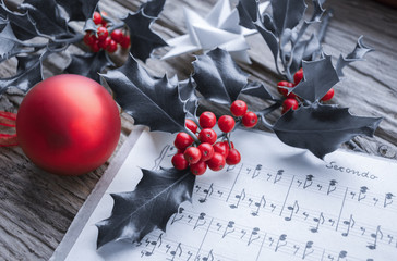 Alte handgeschriebene Musiknoten mit Ilex Zweig, roten Beeren, Weihnachtsstern und roter...