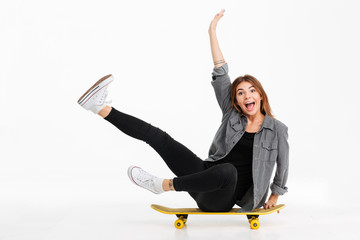 Portrait of a funny crazy girl sitting on a skateboard