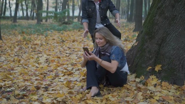 Son makes a surprise to mother in autumn park