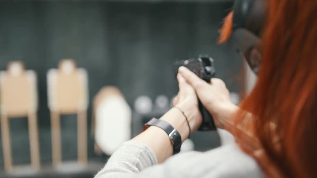 Woman shooting with a pistol gun in shooting gallery