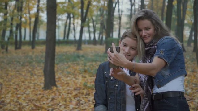 Happy son with mother takes selfie in autumn park