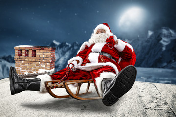 Crazy Santa Claus on a sledge. He's on the roof of the house. Beautiful December night with a big...