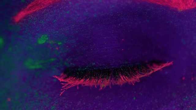 Closeup woman's eye with fluorescent make up open and close, creative makeup look great for nightclubs. Halloween party, shows and music concept - slow motion video