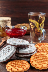 cookies with white chocolate frosting and raspberry jam in a little vase on the table for tea.