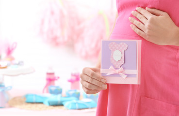 Pregnant woman holding Thank you card for baby shower party indoors