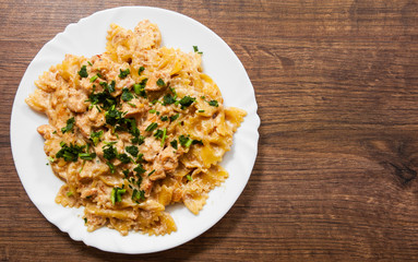 Sliced fried chicken fillet in a creamy sauce. with farfalle pasta. in plate on a wooden background. . with copy space. top view