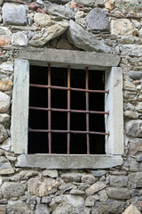 Fototapeta na wymiar window with grilles and stone wall of an ancient stable
