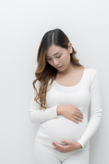 A pregnant woman in white dress standing holding her belly.