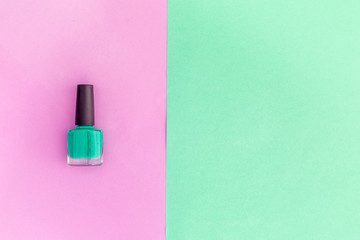 Colorful cosmetics on colorful background. Mint nail polish on pink and mint background top view copyspace