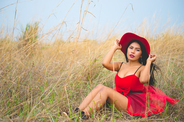 Portrait of asian beautiful woman in red dress with red hat at the field