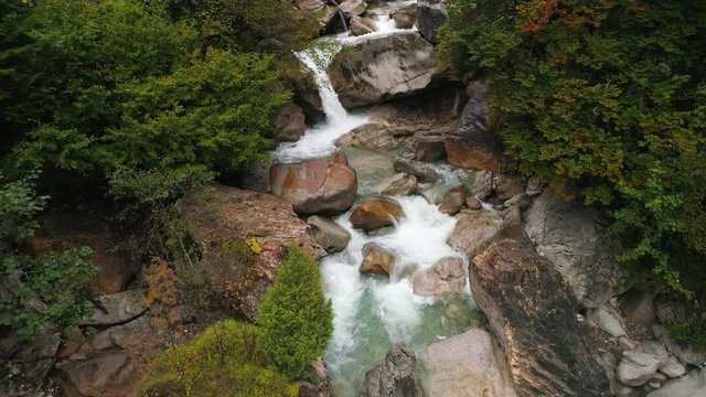 View of Trzic Bistrica River flowing downstream from aerial view following it downstream over small waterfalls in Slovenia.