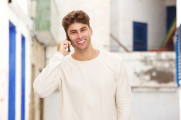 Smiling man standing on city street talking on mobile phone