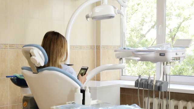 Dentist office, the girl in the chair with the phone and turns smiling at the camera