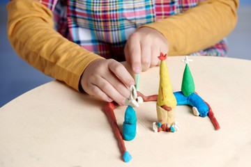 Boy is sculpting with colorful modelling clay. Close up.