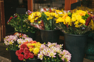 Street shop of flowers - bouquets of peonies and chrysanthemums stand in black buckets.