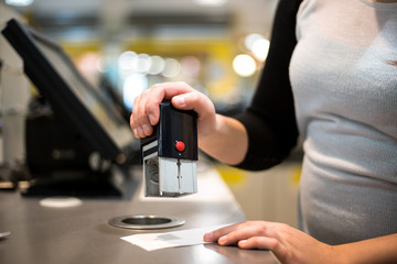 saleswoman / shopgirl giving a stamp on a receipt / invoice for a customer, sales time, discount period