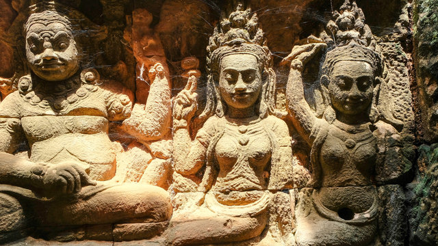 2 apsara ladies and giant bas relief on pink grey sandstone at Angkor Thom, Siem Reap, Cambodia
