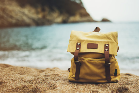 Hipster hiker tourist yellow backpack closeup on background sea enjoying sunset ocean horizon, blurred panoramic seascape sunrise blank mockup, traveler holiday concept, sunlight view in trip vacation
