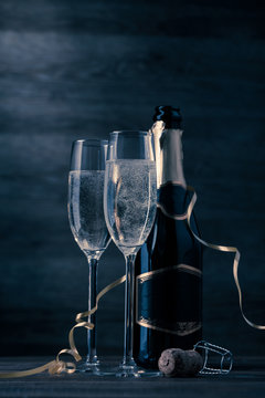 Toned photo of two wine glasses with sparkling champagne, bottle, cork