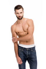 Fototapeta premium Shirtless and sensual. Handsome shirtless young man in jeans looking at camera while standing against white background.