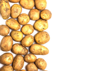 A lot of dirty potatoes on a white background. Potatoes scattered on the left side.
