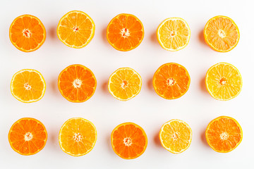 a pattern of orange and yellow mandarins cut in half on a white 