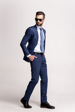 Step to success. Full length of handsome young man in suit and glasses looking away while standing against white background.