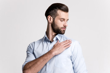 Everything must be perfect. Portrait of handsome young man shaking off dust from his shoulder while standing against white background.